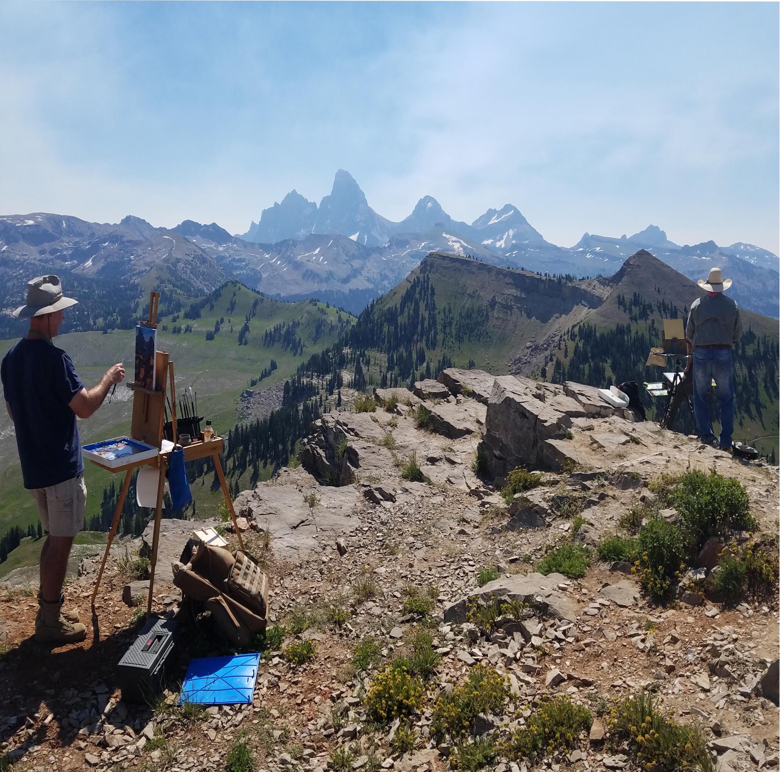 Artists painting on a cliffside the Teton mountains.